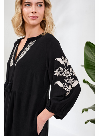 Close-up detail of white floral embroidery and tassel accents on Tribal Elaine Dress against black fabric. 