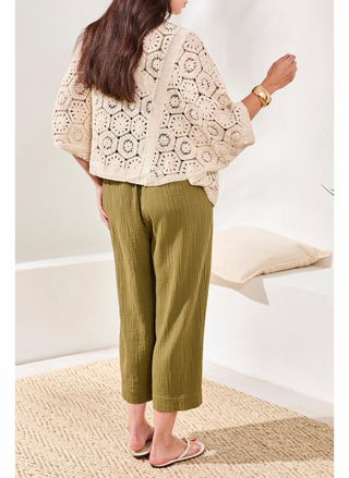 Back view of a woman wearing Tribal Naturally Crochet Cardigan layered over olive gauze jumpsuit.