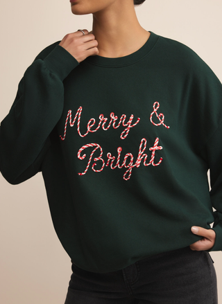 Model wearing Z Supply Bright Sunday Sweatshirt with “Merry & Bright” embroidery in green.