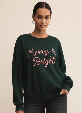 Model wearing Z Supply Bright Sunday Sweatshirt with “Merry & Bright” embroidery in green.