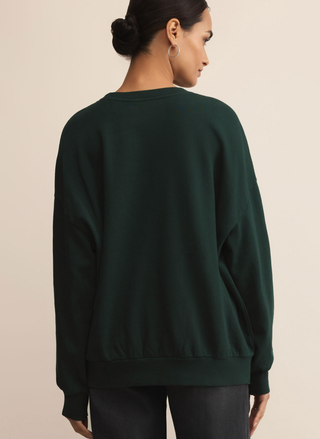 Person wearing a dark green sweatshirt against a beige background