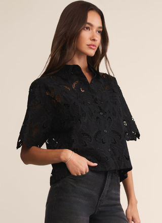 Woman wearing a black lace top against a beige background