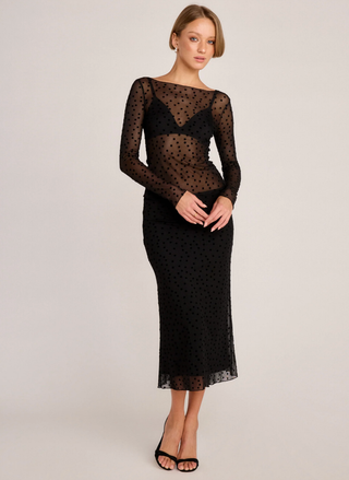 Woman wearing a black lace dress on a plain background