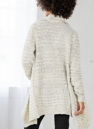 Person wearing a textured cream cardigan against a white background