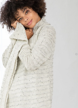 Woman wearing a textured cream cardigan against a plain background