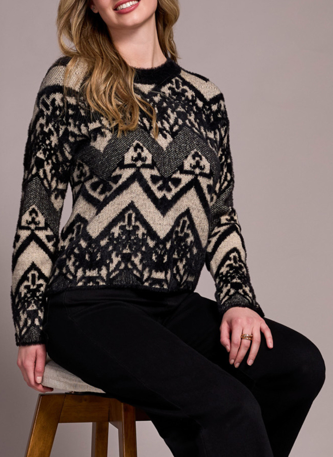Front view of model wearing Tribal Albuquerque Sweater with black and beige geometric pattern, sitting on a stool.