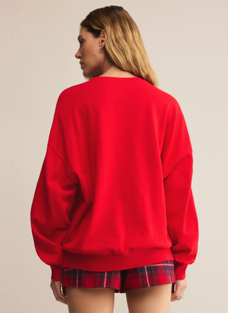 Person wearing a red sweatshirt and plaid shorts on a beige background