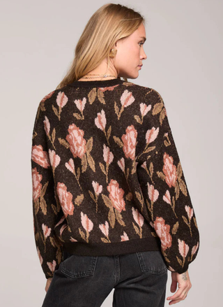 Woman wearing a floral patterned sweater on a plain background