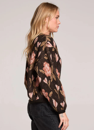 Woman wearing a floral-patterned sweater against a plain background