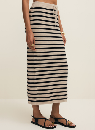 Person wearing a black and white striped skirt on a beige background