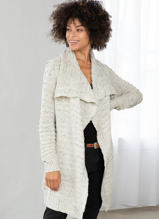 Woman wearing a long, light-colored cardigan against a plain background