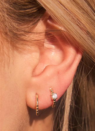 Model wearing Zia Huggies — dainty 18k gold-plated hoops for everyday wear.