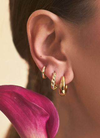 Model wearing Eliza Huggies — gold-plated twisted hoops for everyday elegance.