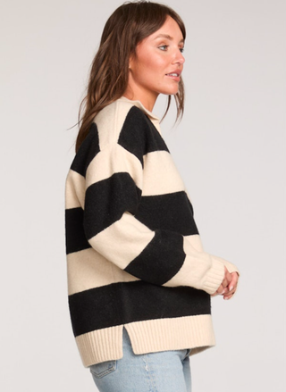 Woman wearing a black and beige striped sweater on a plain background