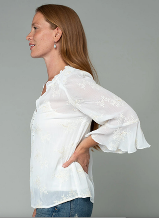 Woman wearing a white blouse with lace details on a gray background