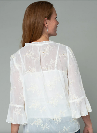 Woman wearing a white lace blouse against a gray background