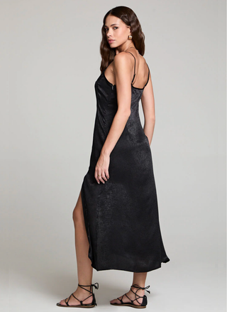 Woman wearing a black slip dress on a plain background