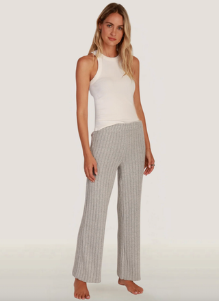 Woman wearing a white sleeveless top and checkered pants on a plain background