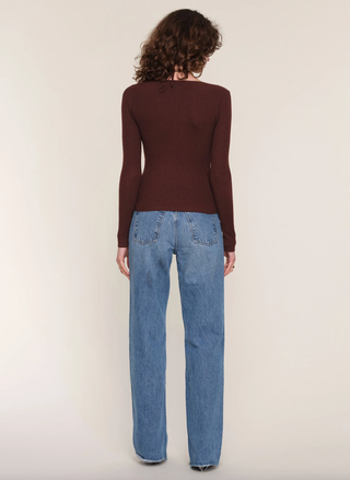 Person wearing a brown long-sleeve top and blue jeans on a white background