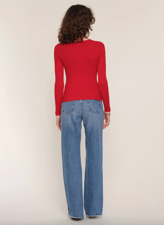Person wearing a red sweater and blue jeans on a plain background