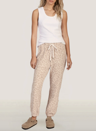 Model wearing neutral cheetah print joggers with a white tank and slip-on suede clogs