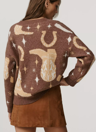 Person wearing a brown sweater with horse and horseshoe pattern on a plain background