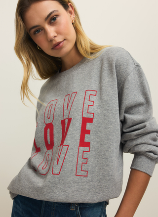 Woman wearing a gray sweatshirt with 'LOVE' printed in red.