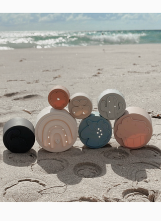 Silicone stacking cups with shape cutouts used as beach sand molds