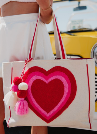 Tote bag with a heart design held by a person, with a blurred background