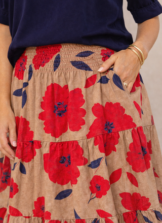 Person wearing a navy top and beige skirt with red floral pattern