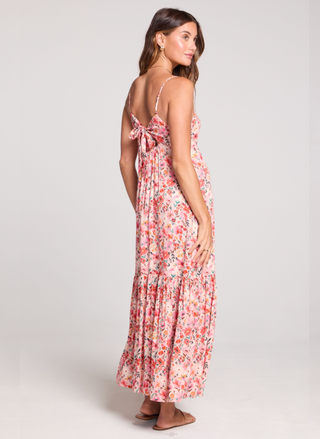 Back view of a woman wearing a floral dress on a white background.