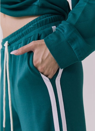 Teal tracksuit with white stripes on a plain background
