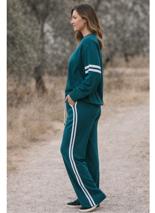 Woman wearing teal Chaser Sandi wide leg sweatpants with white side stripes and drawstring waist