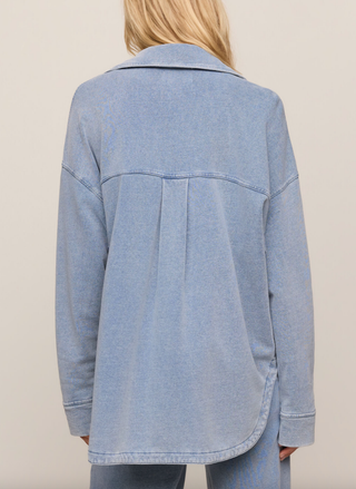 Light blue denim jacket worn by a person on a beige background