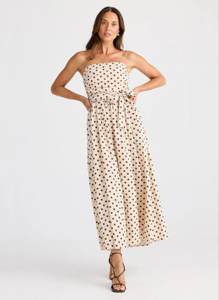 Woman wearing a strapless polka dot dress on a white background