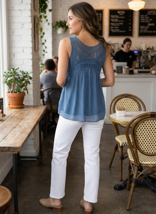 Woman in a blue top and white pants standing in a cafe.