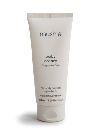 A clean, minimalist white tube of Mushie Baby Cream (100mL) showing the organic and allergy-certified logos.