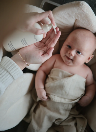 Mother gently applying the fragrance-free wash to her baby's head during bath time.