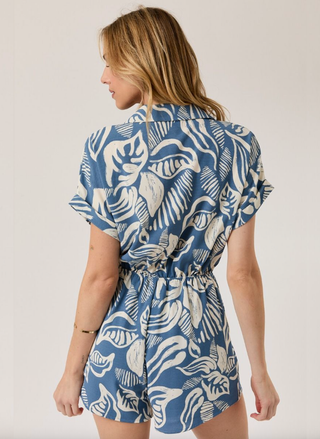 Woman wearing a blue and white patterned romper on a plain background