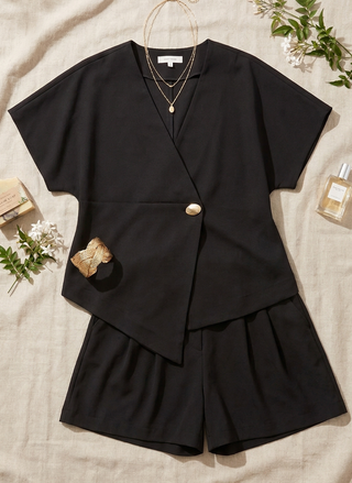 Black outfit with a top and shorts on a neutral background with decorative elements.