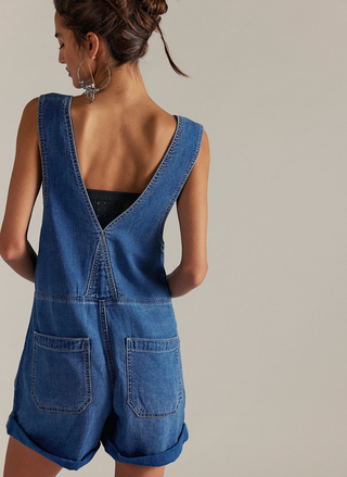 Back view of denim shortall showing V-back design and oversized pockets.