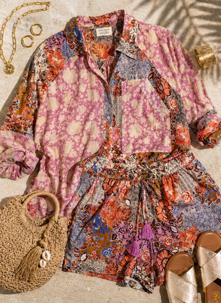 Colorful floral-patterned outfit with a textured handbag on a neutral background