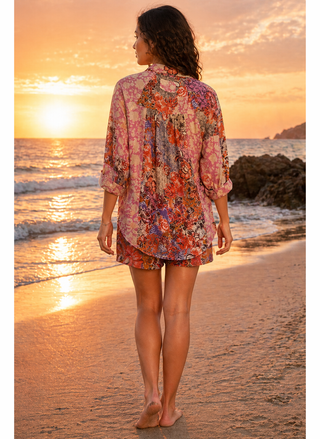 Woman in a printed short set, standing on a beach at sunset