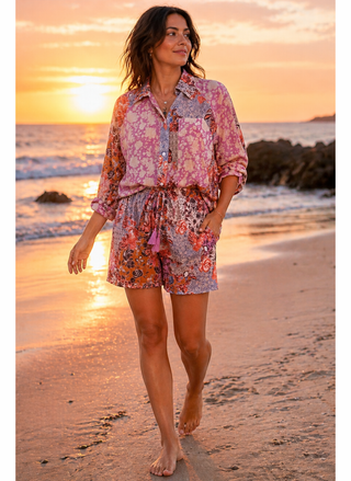 Woman in a floral outfit walking on a beach at sunset