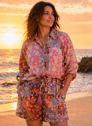 Woman wearing the Tailsman Deam Weaver 100% Cotton printed shirt & short set, standing on a beach at sunset.