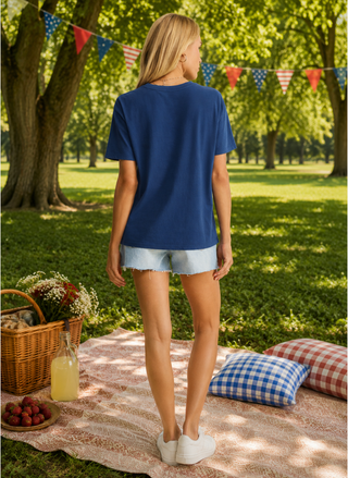 Back view of model wearing navy tee, light wash denim shorts at an outdoor picnic.
