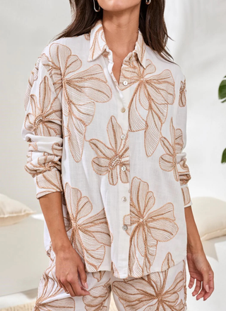 Woman wearing a beige floral pajama set against a white background