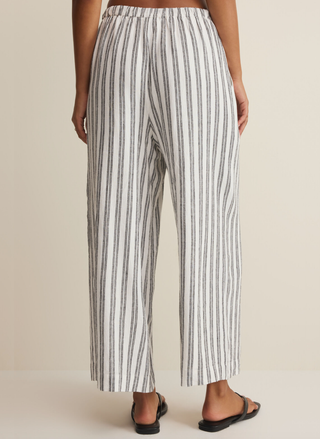 Back view of a model wearing the high-waisted, wide-leg Z Supply striped linen pants in white and black.