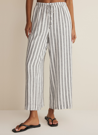 Front view of a model styling the Z Supply The Perfect Striped Pant with the adjustable drawcord waistband and black flat sandals.