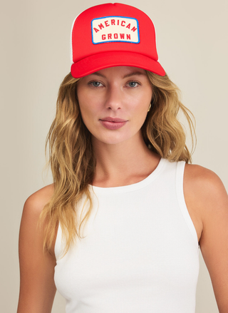 Front view of a model styling the bright red and white Z Supply American Grown Trucker Hat with a casual white tank top.